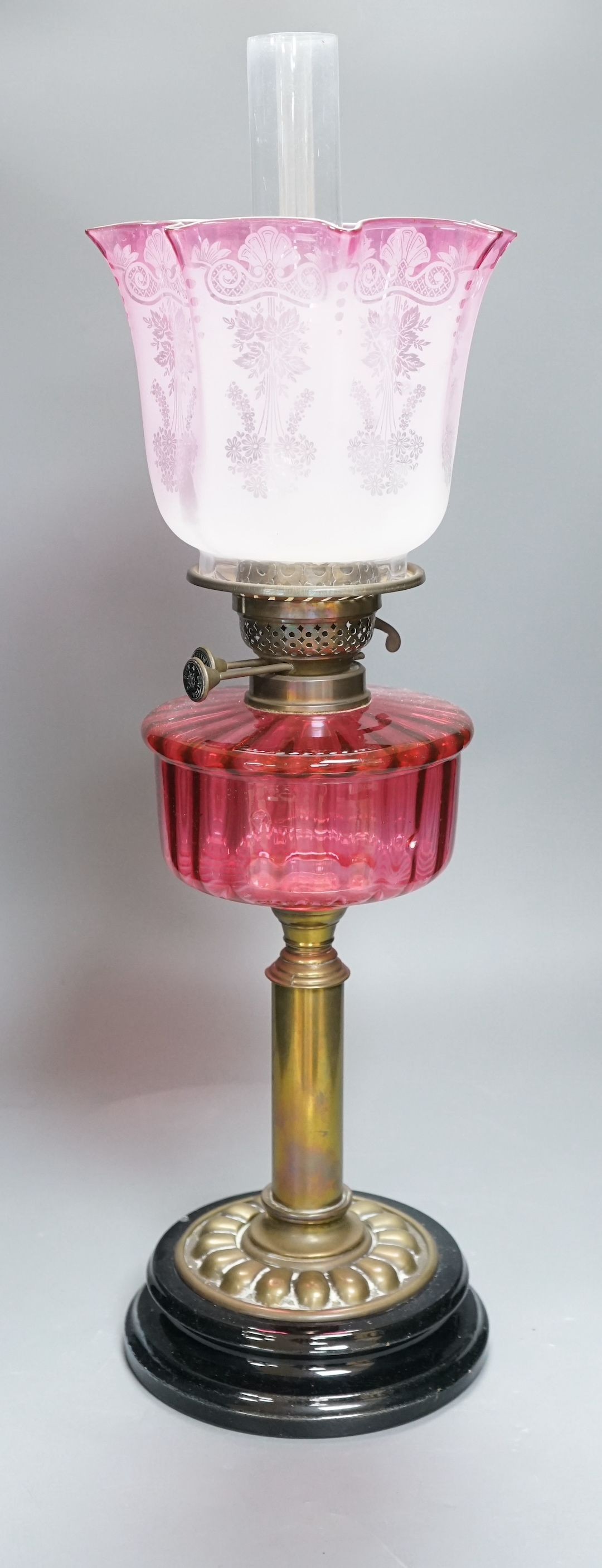 A 19th century cranberry and brass oil lamp with original cranberry shade, height 65cms including glass funnel